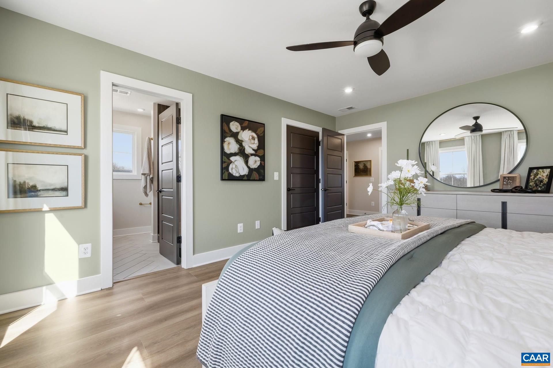 48 B Miranda Crossing Charlottesville, VA 22901 - Photo 17 of 28 a bedroom with a bed ceiling fan and a wooden floor