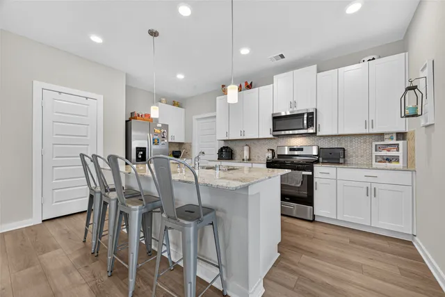 a kitchen with stainless steel appliances granite countertop a sink a stove refrigerator and cabinets