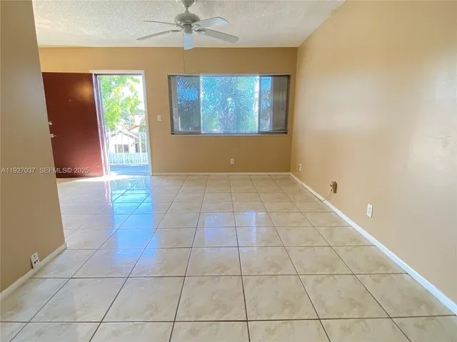 a view of an empty room with window and chandelier fan