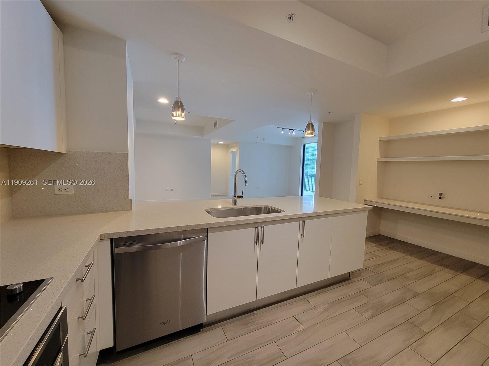 999 Southwest 1st Avenue, Unit 2016 Miami, FL 33130 - Photo 11 of 49 a large white kitchen with a sink and dishwasher stove top oven with wooden floor