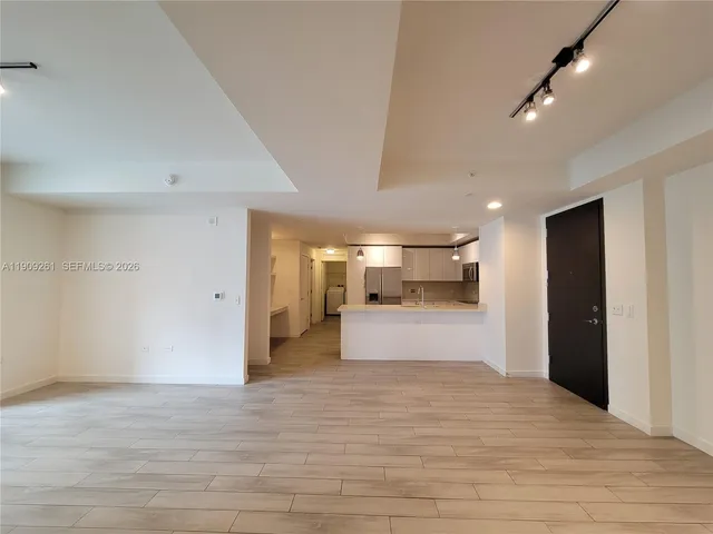 a view of an empty room with wooden floor and windows