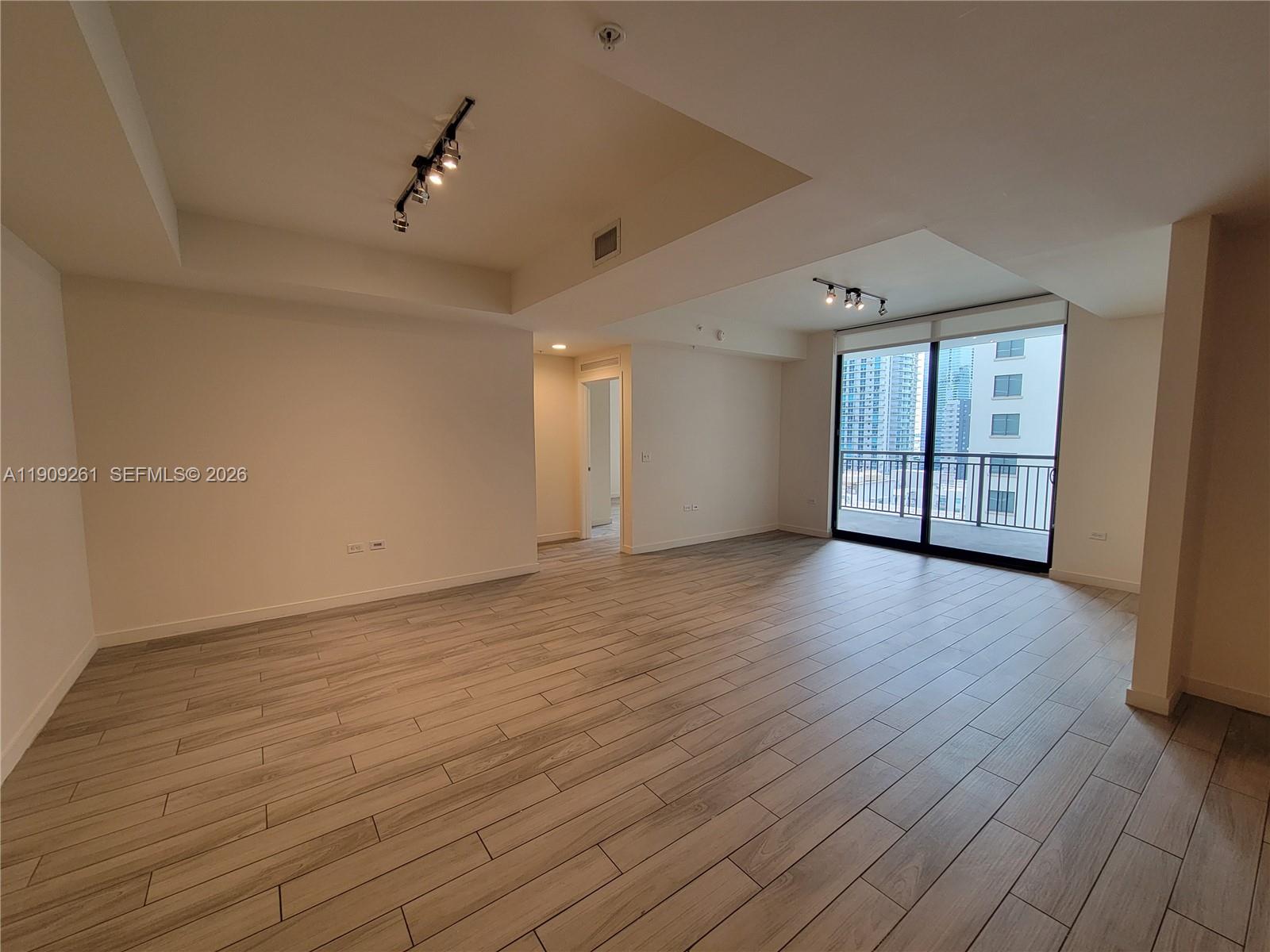 999 Southwest 1st Avenue, Unit 2016 Miami, FL 33130 - Photo 17 of 49 an empty room with wooden floor and windows
