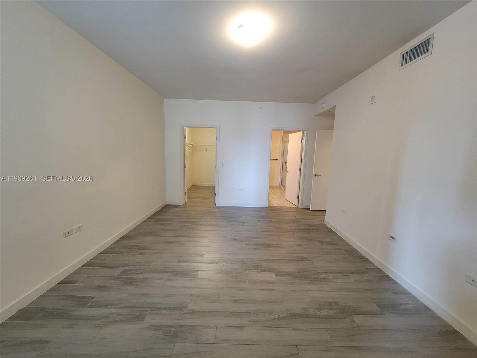 999 Southwest 1st Avenue, Unit 2016 Miami, FL 33130 - Photo 20 of 49 a view of an empty room with wooden floor and windows