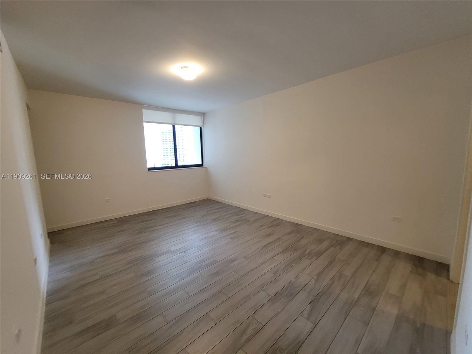 999 Southwest 1st Avenue, Unit 2016 Miami, FL 33130 - Photo 21 of 49 an empty room with wooden floor and windows