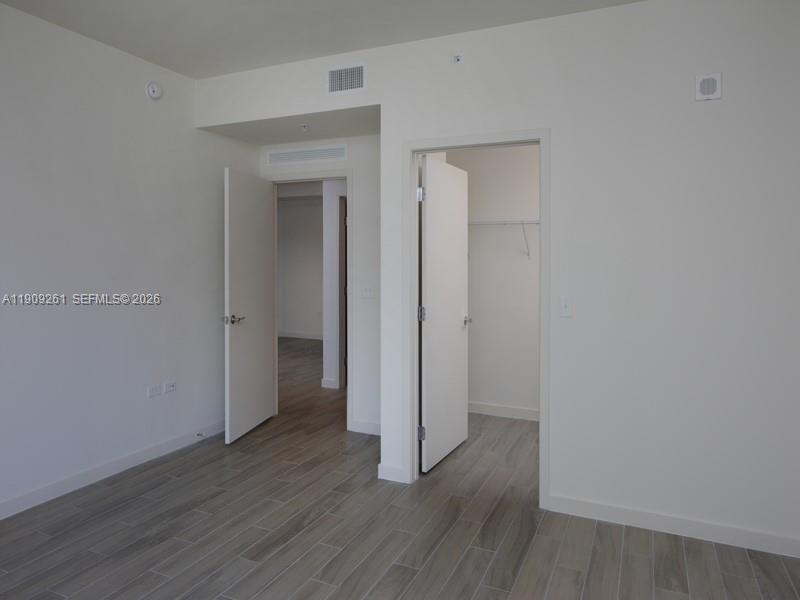 999 Southwest 1st Avenue, Unit 2016 Miami, FL 33130 - Photo 33 of 49 an empty room with wooden floor & closet area