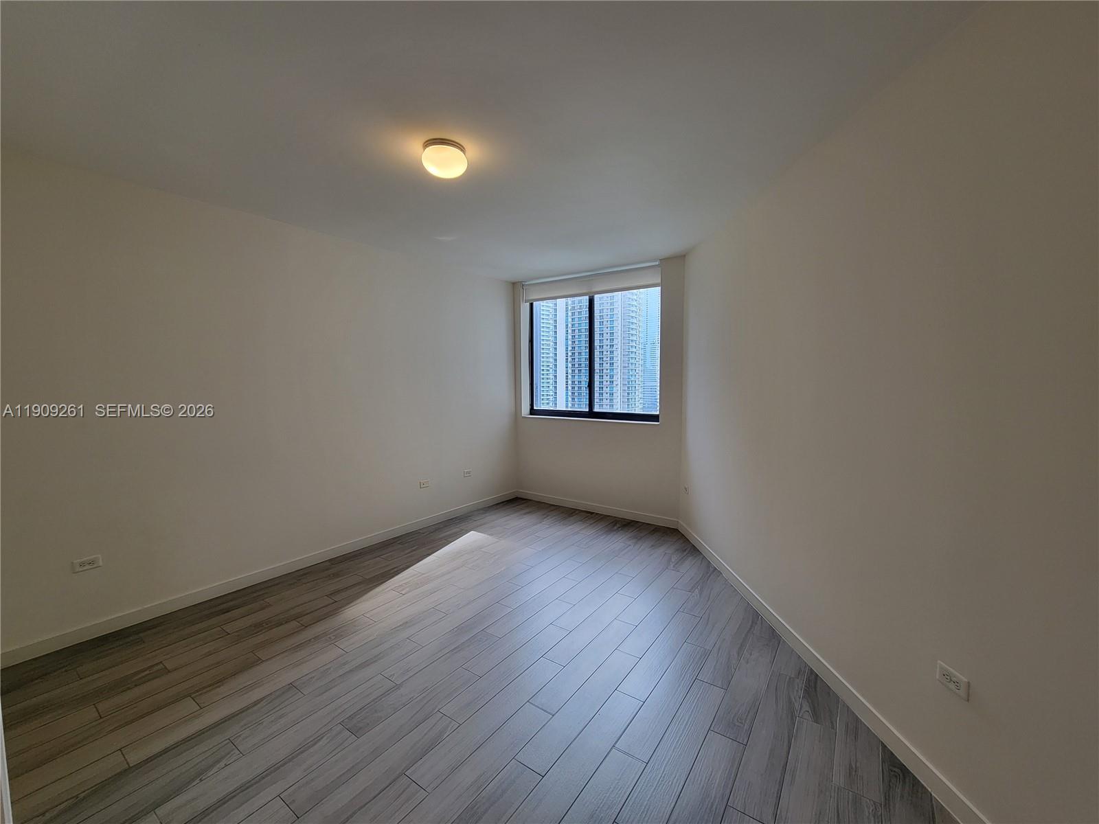 999 Southwest 1st Avenue, Unit 2016 Miami, FL 33130 - Photo 35 of 49 an empty room with wooden floor and windows