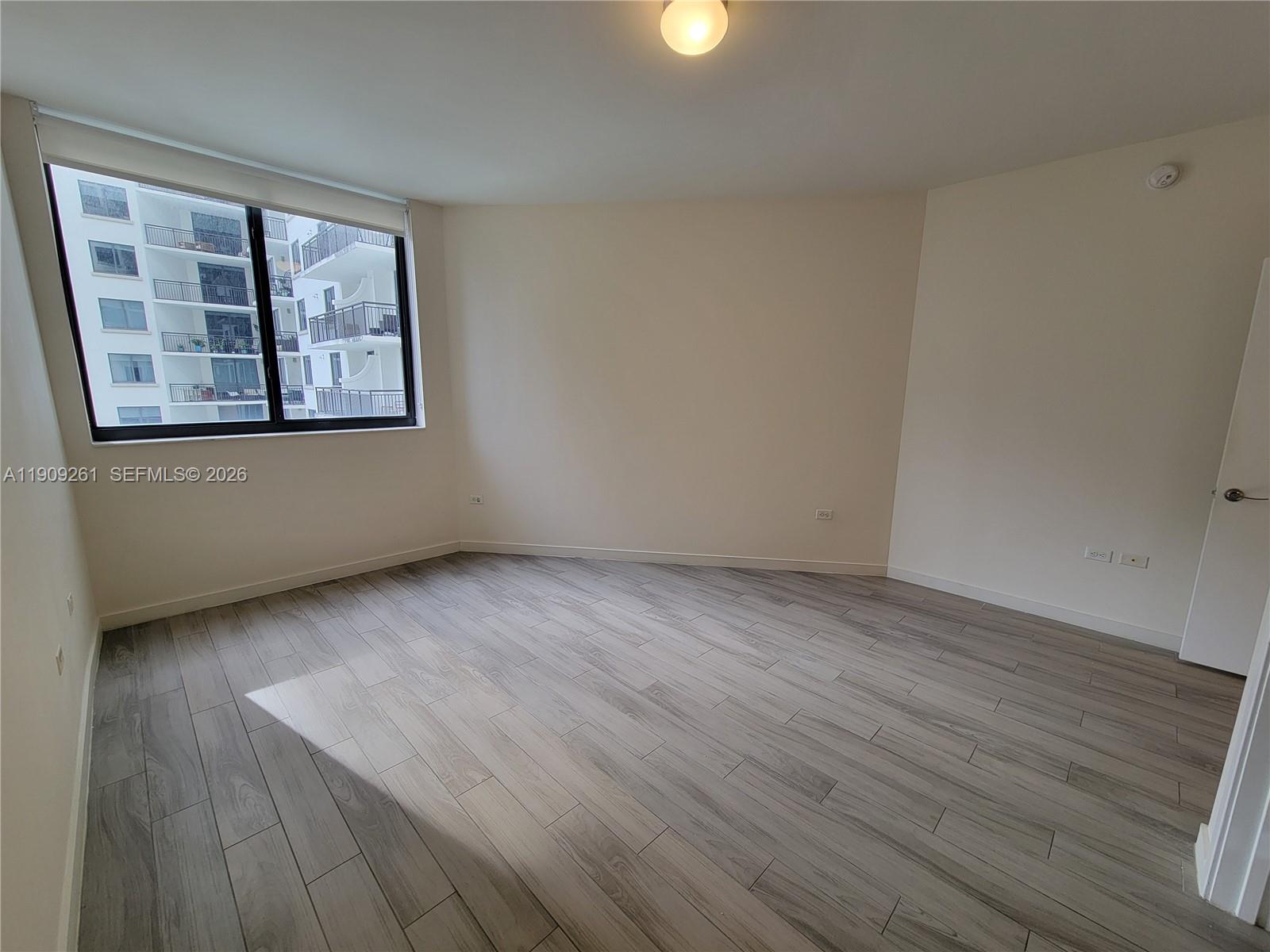 999 Southwest 1st Avenue, Unit 2016 Miami, FL 33130 - Photo 36 of 49 an empty room with wooden floor and window