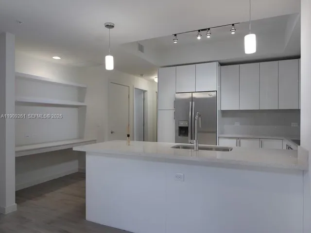 a large white kitchen with a sink and dishwasher stove top oven with wooden floor