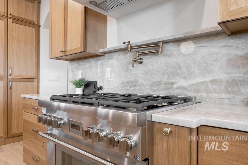 3322 South Volunteer Place Meridian, ID 83642 - Photo 22 of 50 Kitchen with decorative backsplash, high end stainless steel range, and light stone countertops