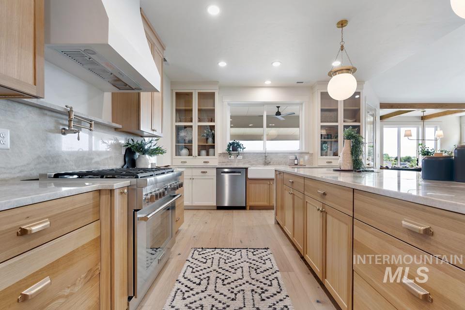 3322 South Volunteer Place Meridian, ID 83642 - Photo 25 of 50 Kitchen with light brown cabinets, appliances with stainless steel finishes, wall chimney exhaust hood, light stone countertops, and beam ceiling