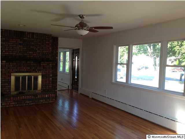 815 Tennent Road Manalapan, NJ 07726 - Photo 3 of 18 a view of a livingroom with a fireplace wooden floor and windows