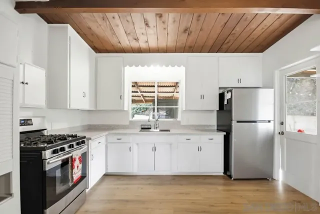 a kitchen with stainless steel appliances a refrigerator a stove a sink and white cabinets