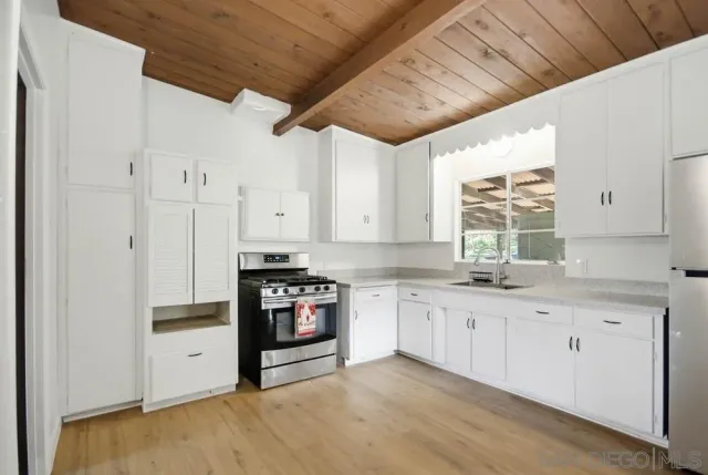 a kitchen with granite countertop a sink cabinets stainless steel appliances and a window