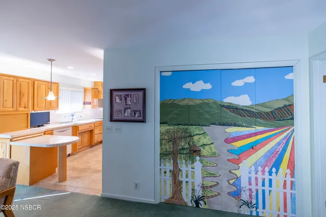 a living room with a dining table chairs and a refrigerator