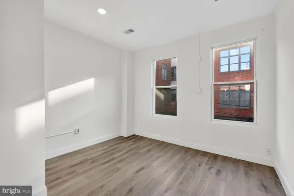 an empty room with wooden floor and windows