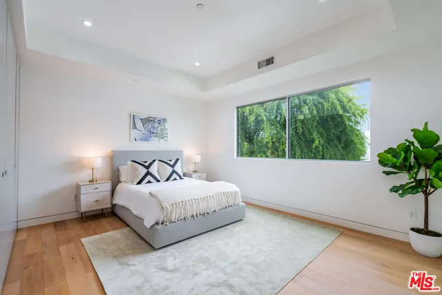 a bedroom with a large bed and a potted plant