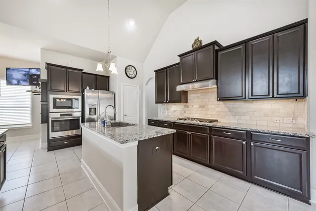 a kitchen with stainless steel appliances granite countertop a stove refrigerator and cabinets