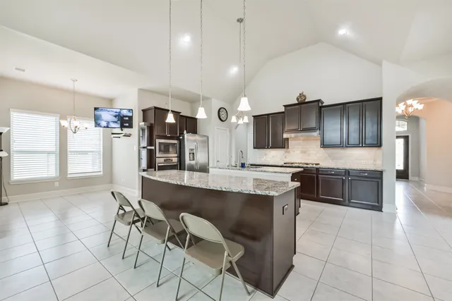 a large kitchen with a large counter top space a sink stainless steel appliances and cabinets