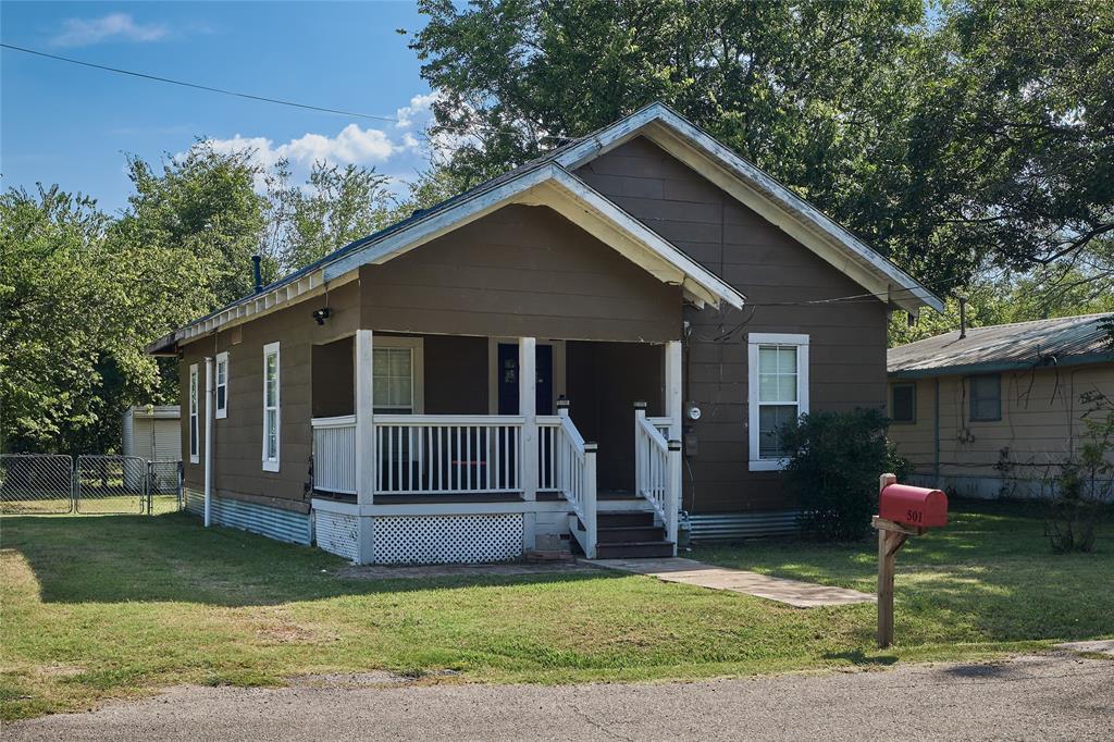 a front view of a house with a garden and trees