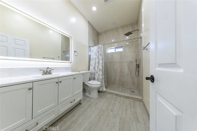 a spacious bathroom with a double vanity sink toilet mirror and shower