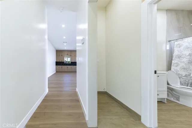 a view of a hallway with wooden floor and a bathroom