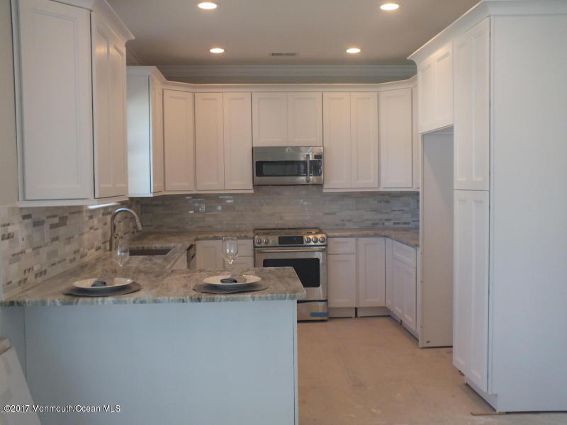 301 Leeward Road Manahawkin, NJ 08050 - Photo 3 of 11 a kitchen with granite countertop white cabinets and stainless steel appliances