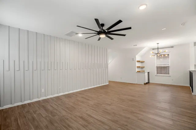 a view of an empty room with a window and wooden floor