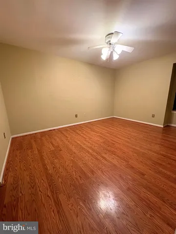 an empty room with wooden floor and fan