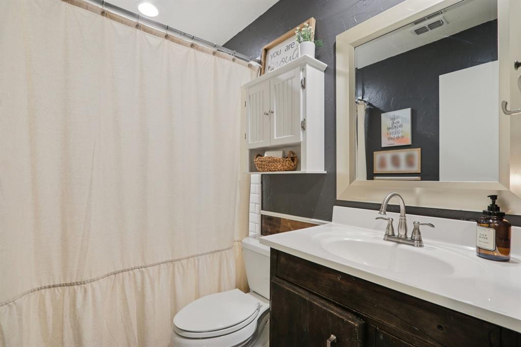 149 South Moore Road Coppell, TX 75019 - Photo 23 of 40 a bathroom with a sink a toilet a mirror and shower curtain
