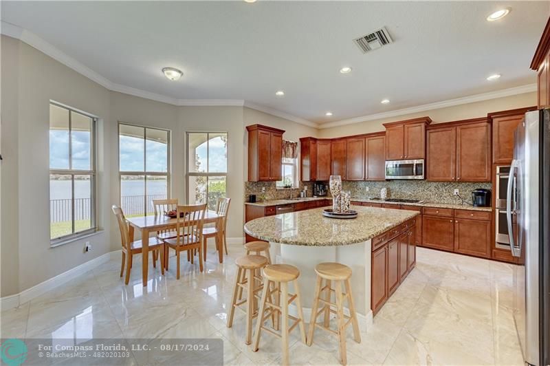 8631 Lakeside Bend Parkland, FL 33076 - Photo 19 of 71 a large kitchen with kitchen island granite countertop a stove a sink a dining table and chairs
