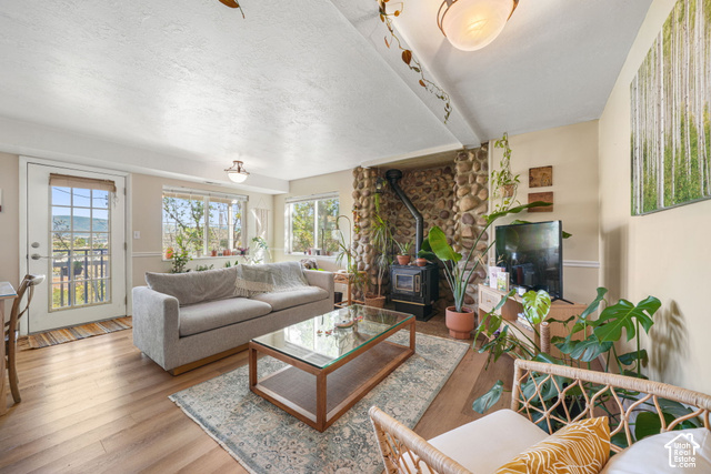 380 Luzern Road Midway, UT 84049 - Photo 28 of 41 Wood-finish flooring, multiple windows, stone-clad fireplace with wood stove, and an exterior door with glass panels