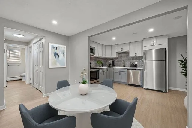 a kitchen with stainless steel appliances kitchen island granite countertop a dining table chairs refrigerator and sink