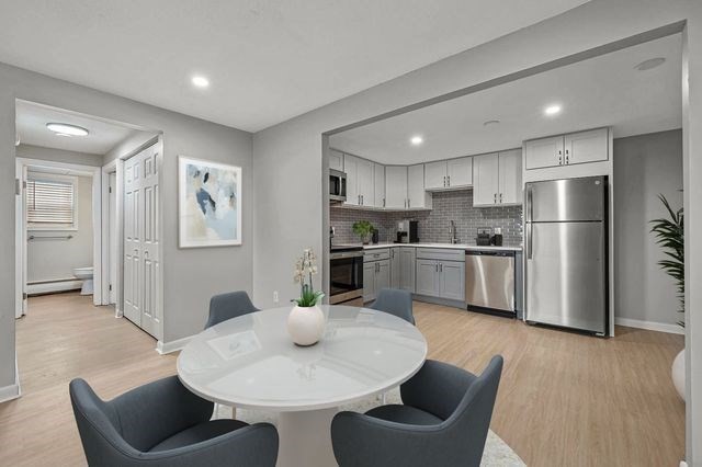 a kitchen with stainless steel appliances kitchen island granite countertop a dining table chairs refrigerator and sink