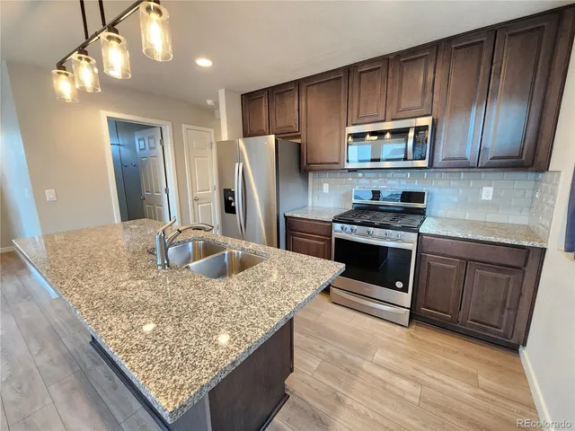 a kitchen with stainless steel appliances granite countertop a sink stove and refrigerator