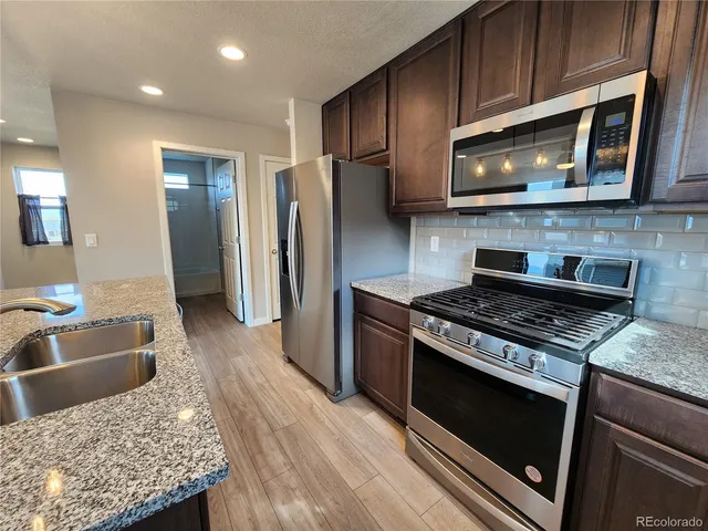 a kitchen with stainless steel appliances granite countertop a stove microwave and refrigerator