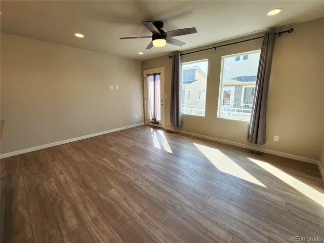 a view of an empty room with a window and wooden floor