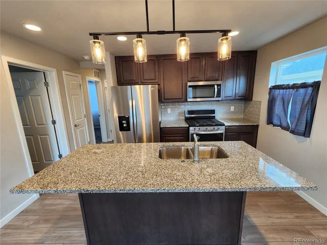 a kitchen with stainless steel appliances granite countertop a refrigerator a stove a sink a microwave a refrigerator and island