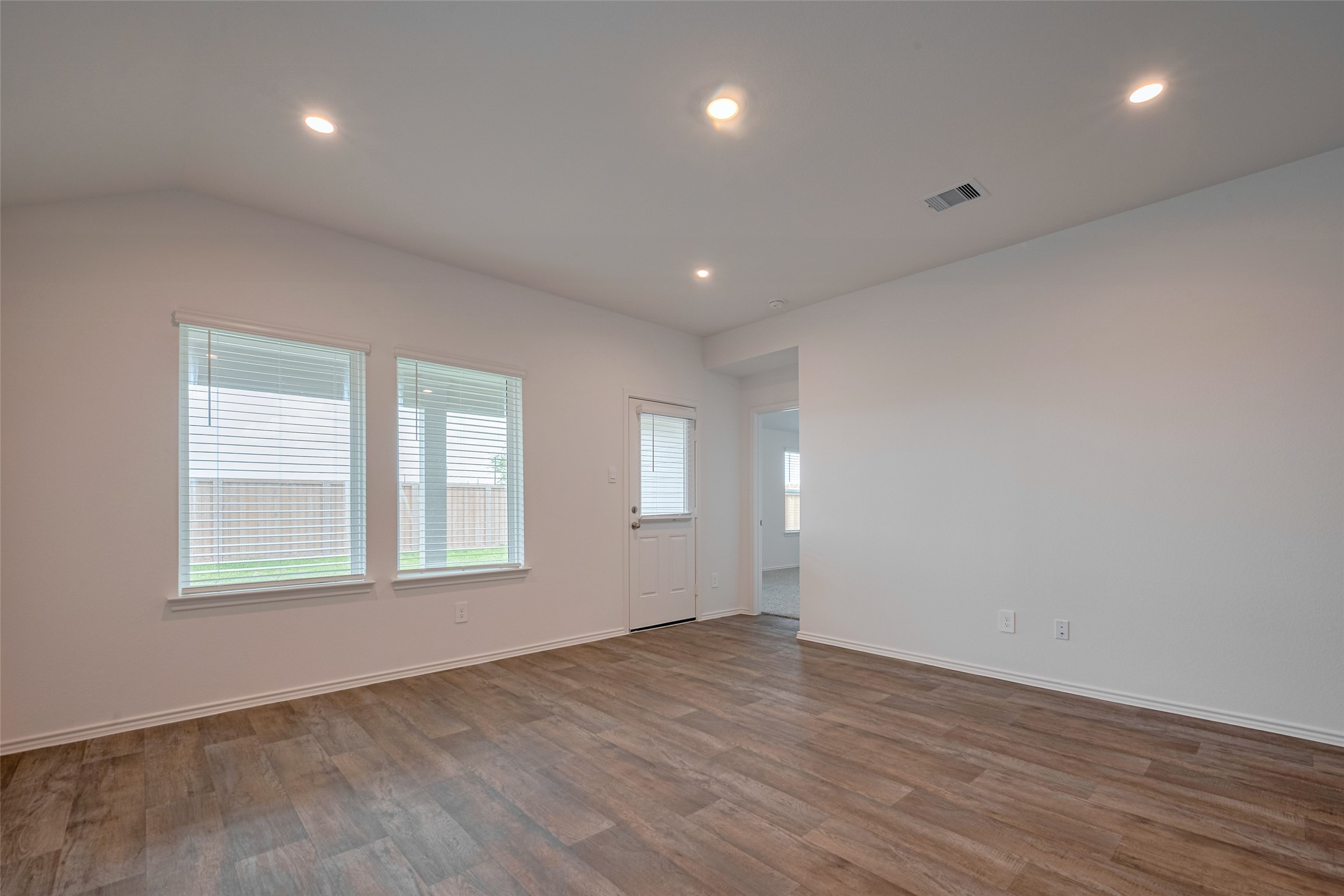30910 Rockstock Road Fulshear, TX 77441 - Photo 8 of 33 Spacious and inviting family room with an open layout, wood-look flooring, and recessed lighting. Natural light pours in through the windows, creating a bright and airy space—perfect for relaxing or entertaining