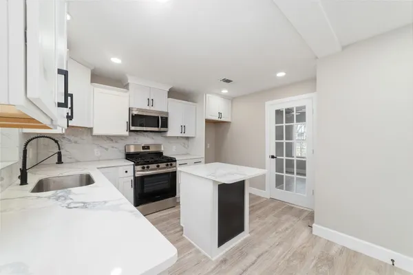 a kitchen with stainless steel appliances granite countertop a sink a stove a refrigerator cabinets and a microwave oven