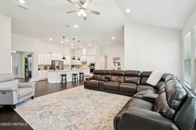 a kitchen with stainless steel appliances granite countertop a refrigerator a sink dishwasher a dining table and chairs with wooden floor