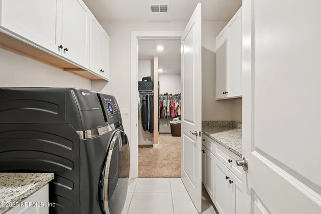 a view of kitchen with stainless steel appliances granite countertop a stove a sink and white cabinets with island next to windows