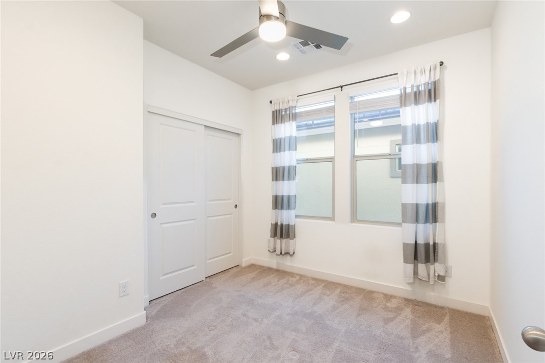 920 East Sunset Road Henderson, NV 89011 - Photo 20 of 33 A well-lit bedroom features plush carpeting and a modern ceiling fan for ultimate comfort.