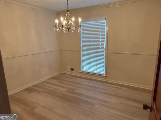 a view of empty room with window and chandelier