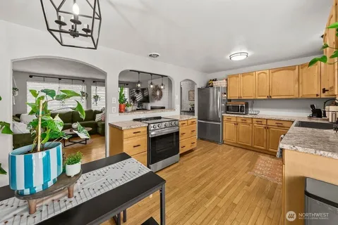 a kitchen with stainless steel appliances kitchen island granite countertop a stove a sink dishwasher and a refrigerator with wooden floor