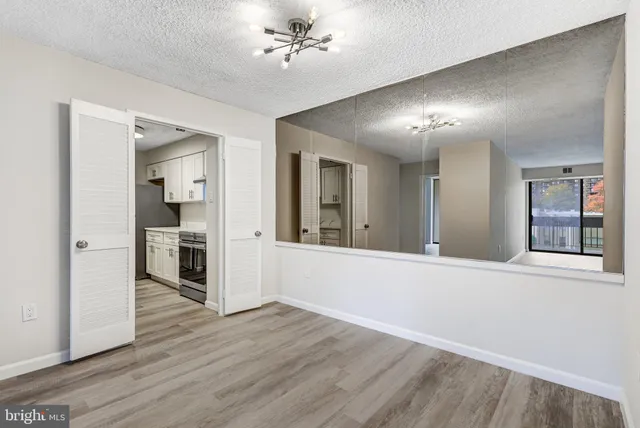 a view of a hallway with wooden floor and a kitchen