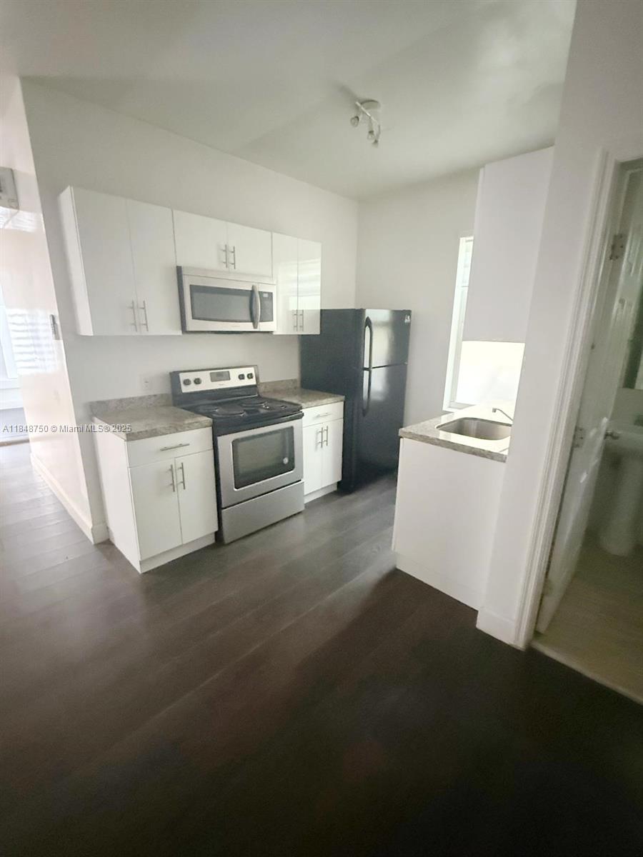 337 Southwest 10th Avenue, Unit 3 Miami, FL 33130 - Photo 2 of 7 a kitchen with stainless steel appliances a sink a stove a refrigerator cabinets and a window