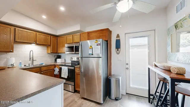 a kitchen with stainless steel appliances granite countertop a refrigerator a sink dishwasher a stove and a dining table with wooden floor