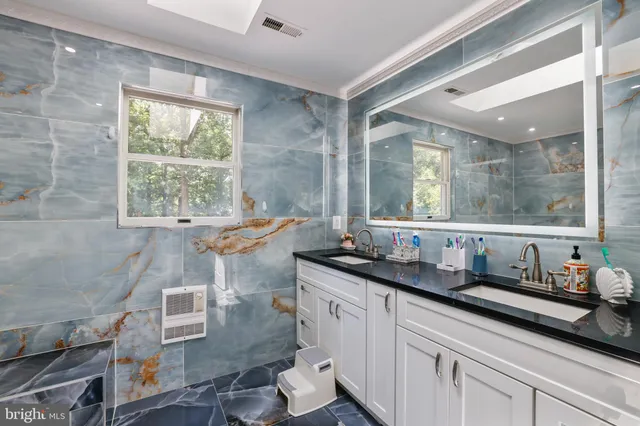 a bathroom with a sink mirror toilet and next to a window