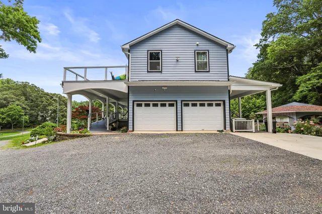 a front view of a house with garden and trees