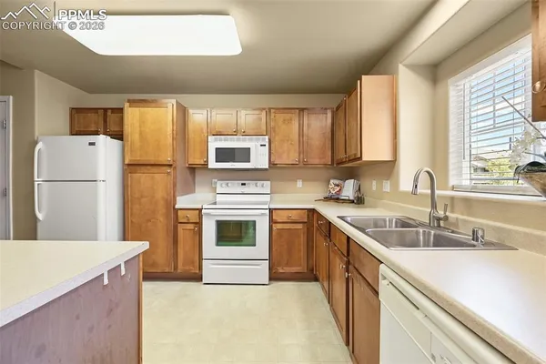 a kitchen with a sink white cabinets and white appliances